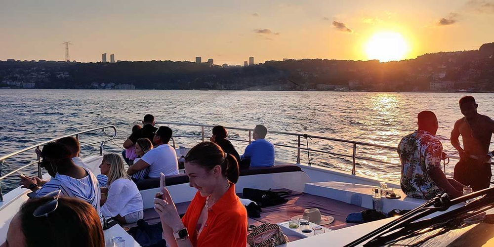 People enjoying the stunning sunset view aboard a Bosphorus yacht cruise.
